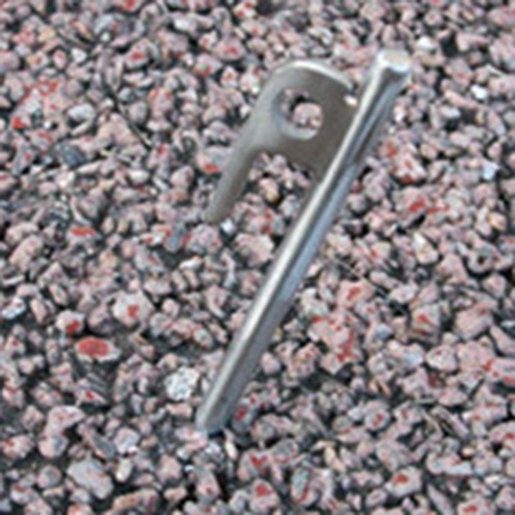 Stainless steel tent stake peg partially driven into gravel