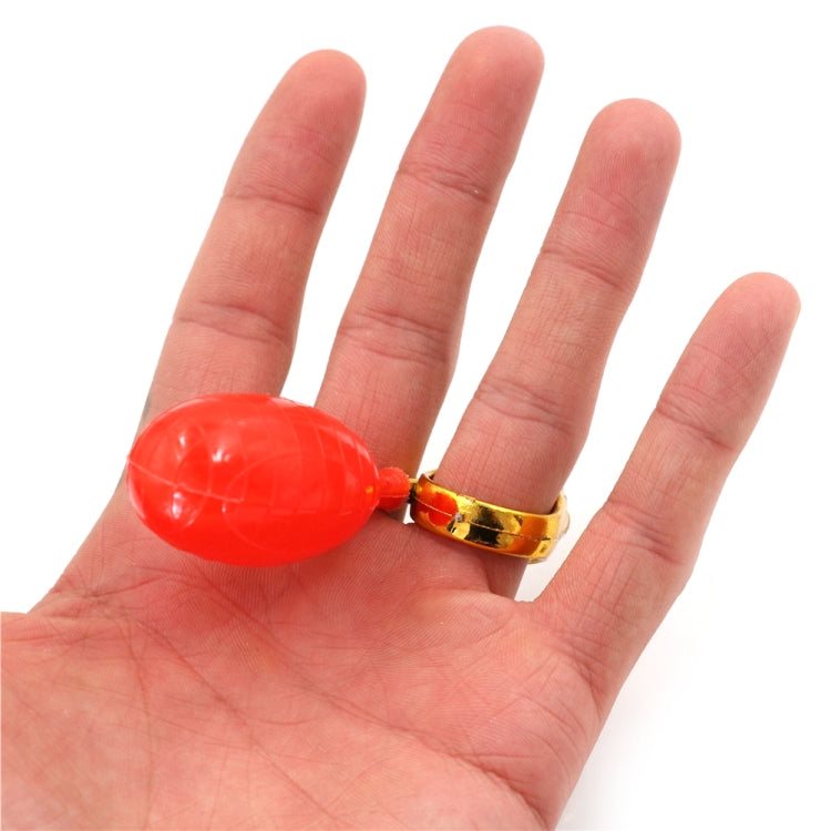 Red squeeze bulb ring toy with gold lion-face band on open palm