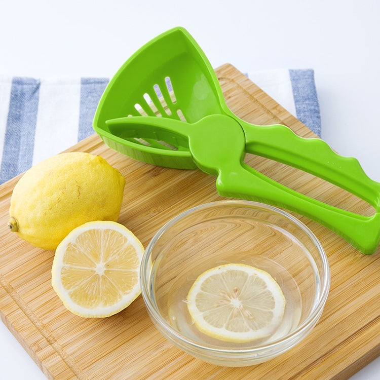Green lemon juice extractor on wooden board beside lemon halves and bowl