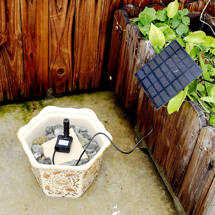 Solar fountain pump and solar panel beside ceramic basin with flowing spray