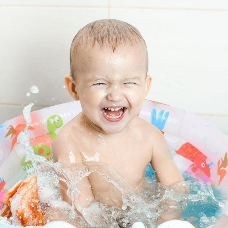 Baby splashing in round inflatable pool with cartoon dinosaur print