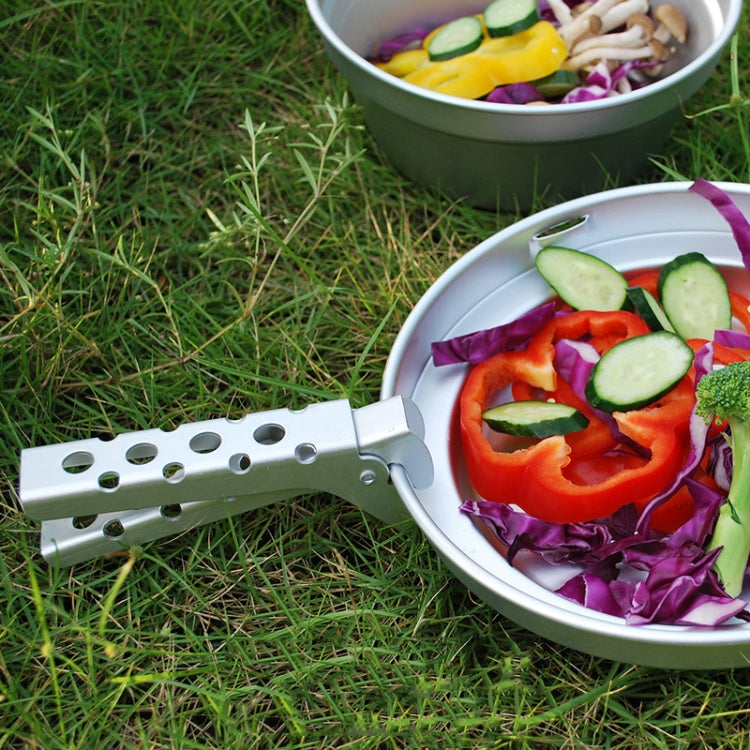 Aluminum BBQ pot tongs resting near a plate of vegetables outdoors