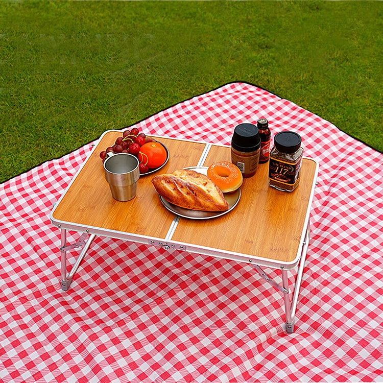 Red check picnic mat with wooden table, snacks, and three bottles on top