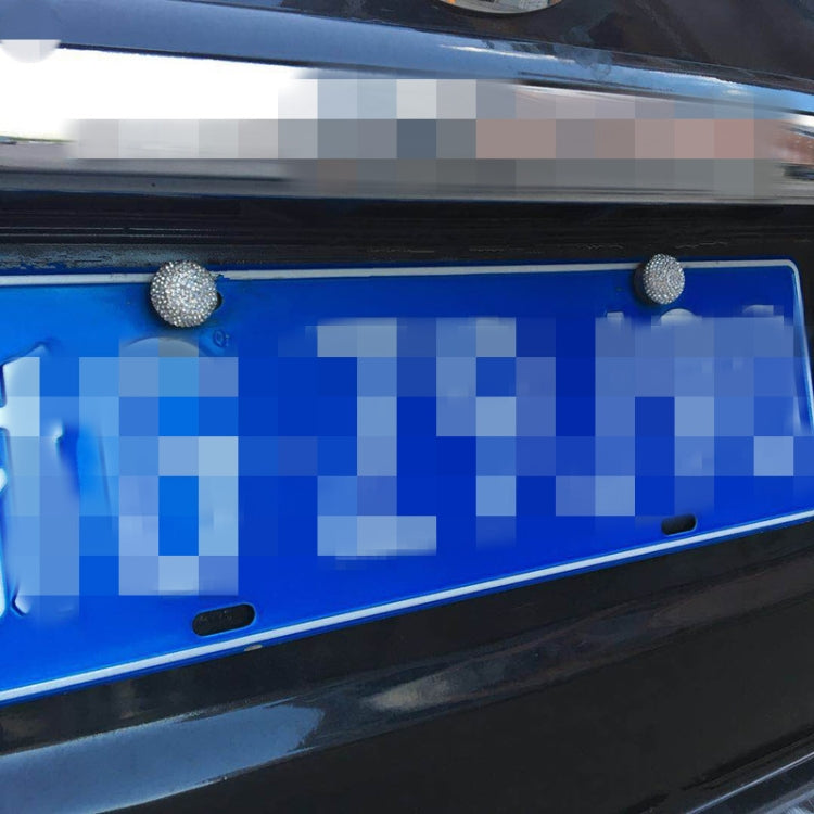 Red rhinestone screw caps on a blue license plate, covering mounting holes