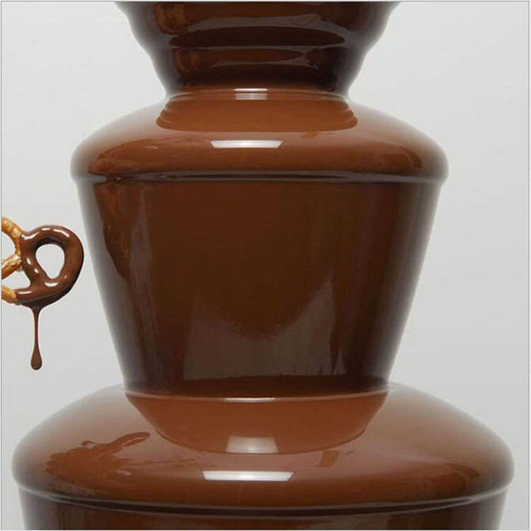 Glossy dark chocolate flowing over the top of a four-tier chocolate fountain