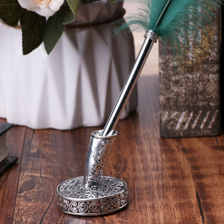 Antique metal pen holder holding a pen on a round engraved base