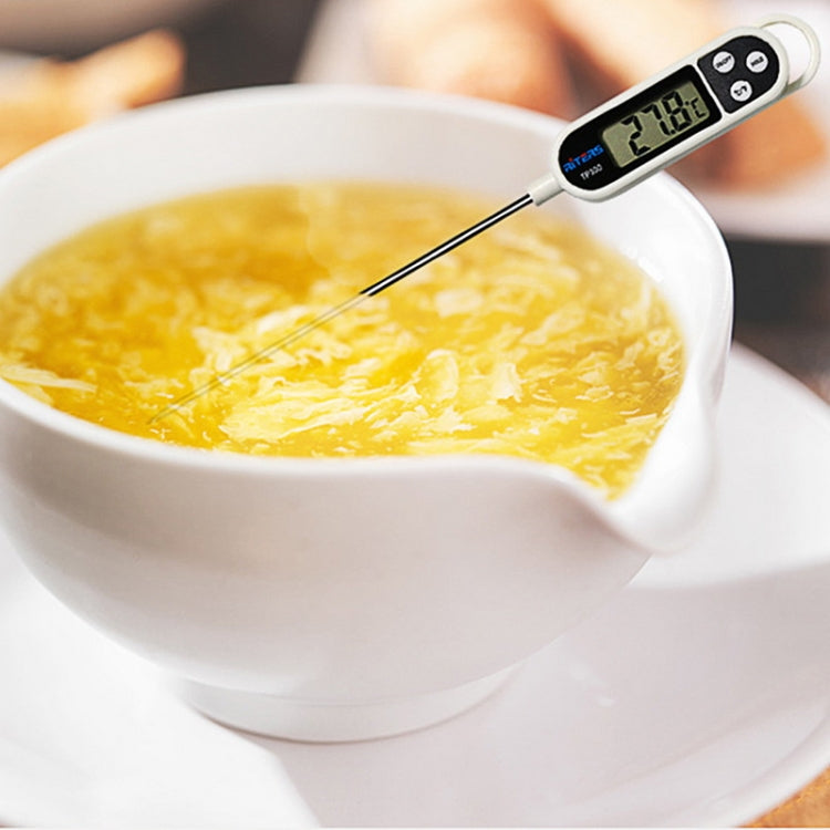 Digital food thermometer with stainless probe in soup, showing temperature on LCD