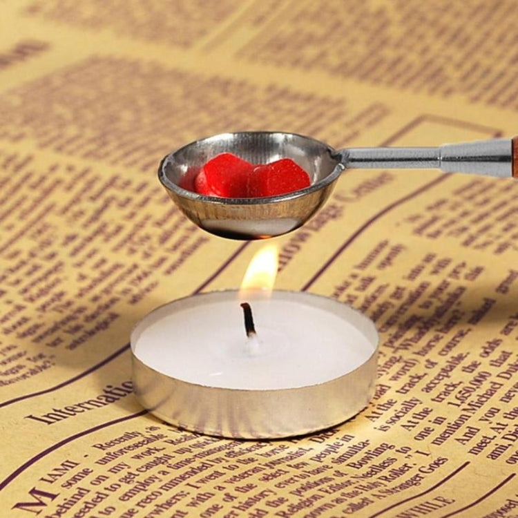 Seal wax spoon with silver bowl melting red wax over a lit candle