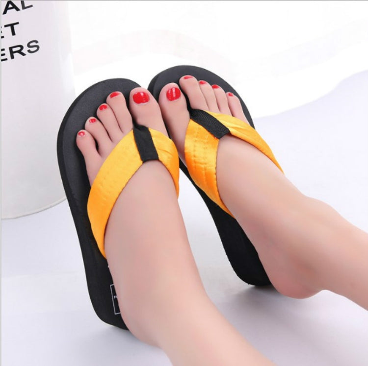 Orange wedge flip-flops with black thong straps worn with red toenails