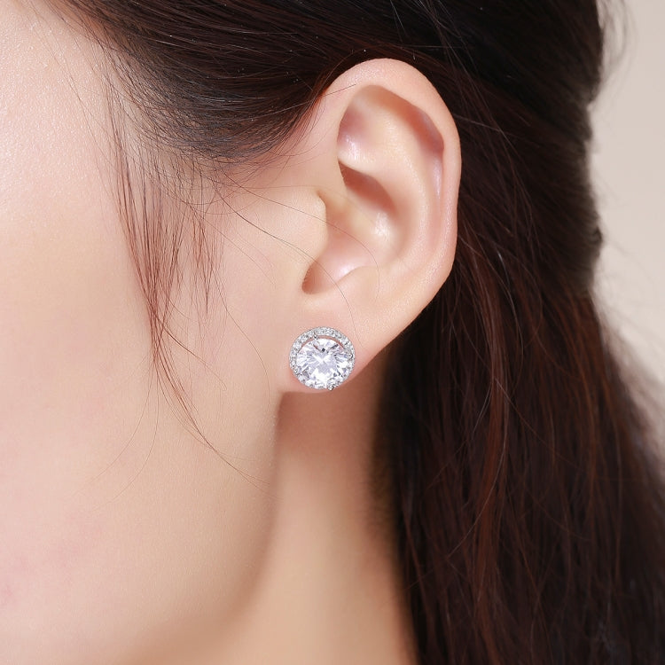 Silver CZ stud earrings on a young woman's ear, round halo design