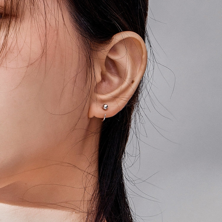 Silver ball hoop earrings worn, featuring small round spheres on hoop wires