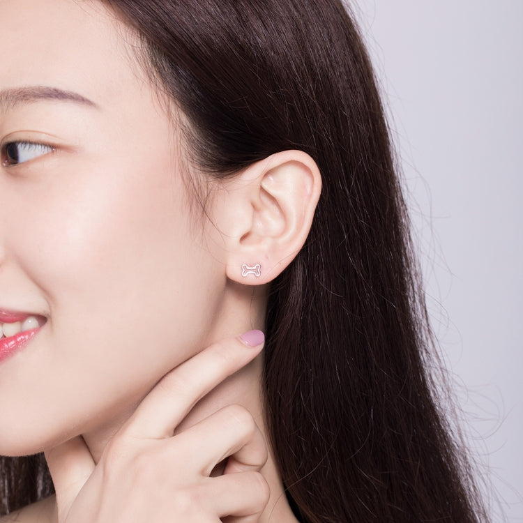 Sterling silver dog bone stud earrings on model with hand near ear