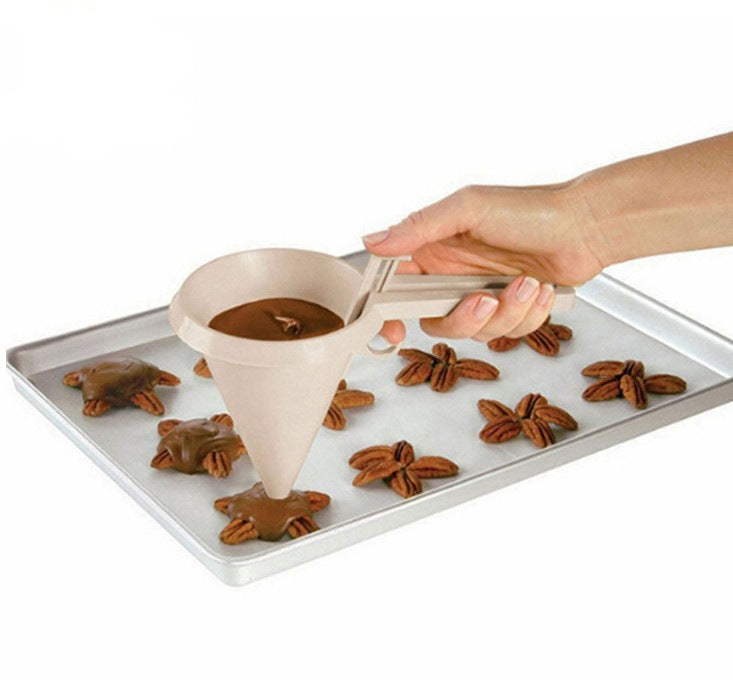 White frosting funnel dispenser pouring onto a tray of cupcakes