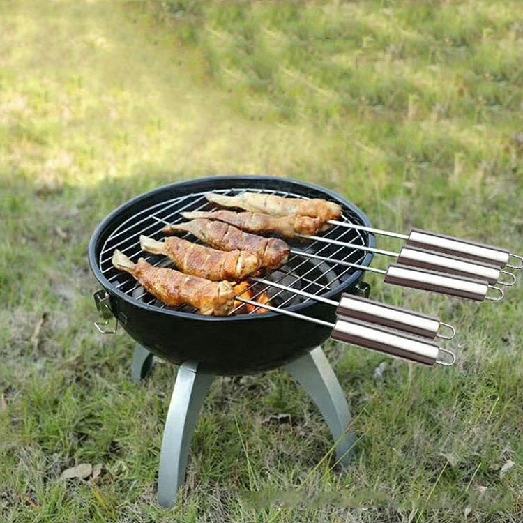 Stainless steel BBQ skewers on grill grate with cooked meat portions