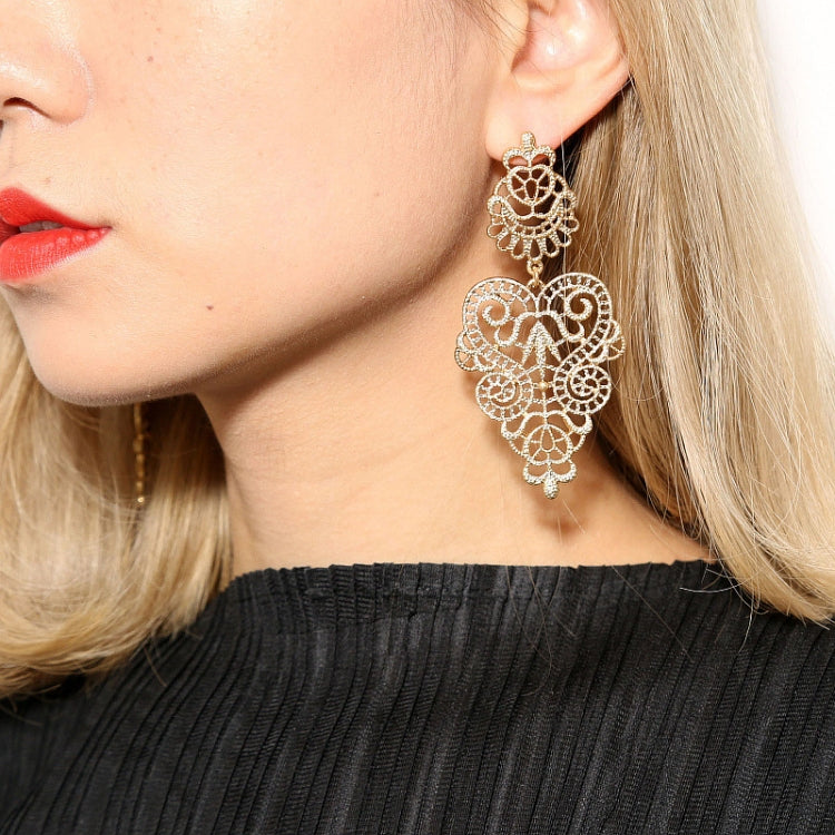 Filigree pendant drop earrings with round medallion design, worn