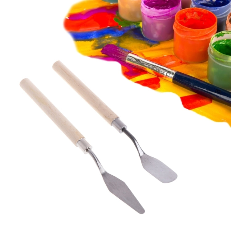 Pair of stainless steel palette knives with light wood handles next to paint colors