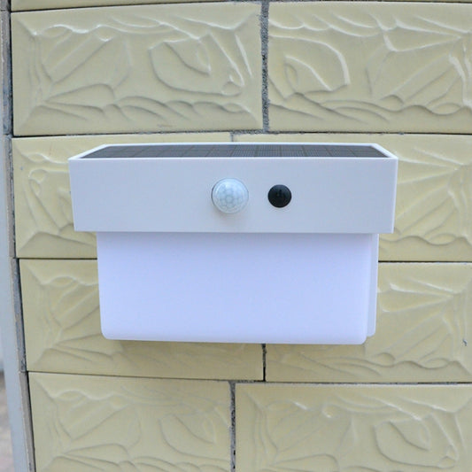 White solar wall light mounted on textured wall with solar panel and sensor