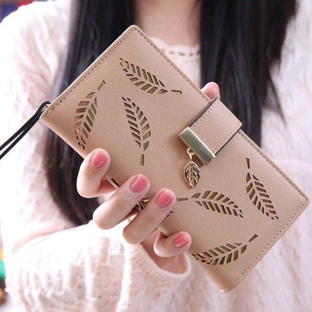 Long coin purse card holder wallet, beige, gold-tone clasp and hollow leaf cutout detail.