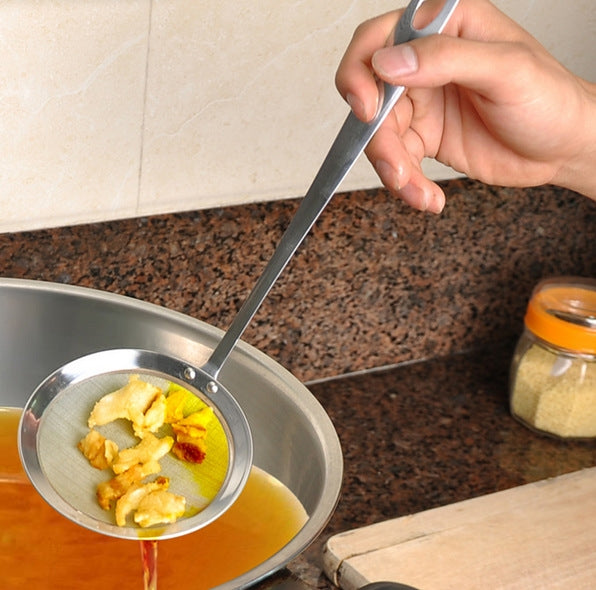 Hand holding stainless steel mesh skimmer strainer dipping into pot liquid