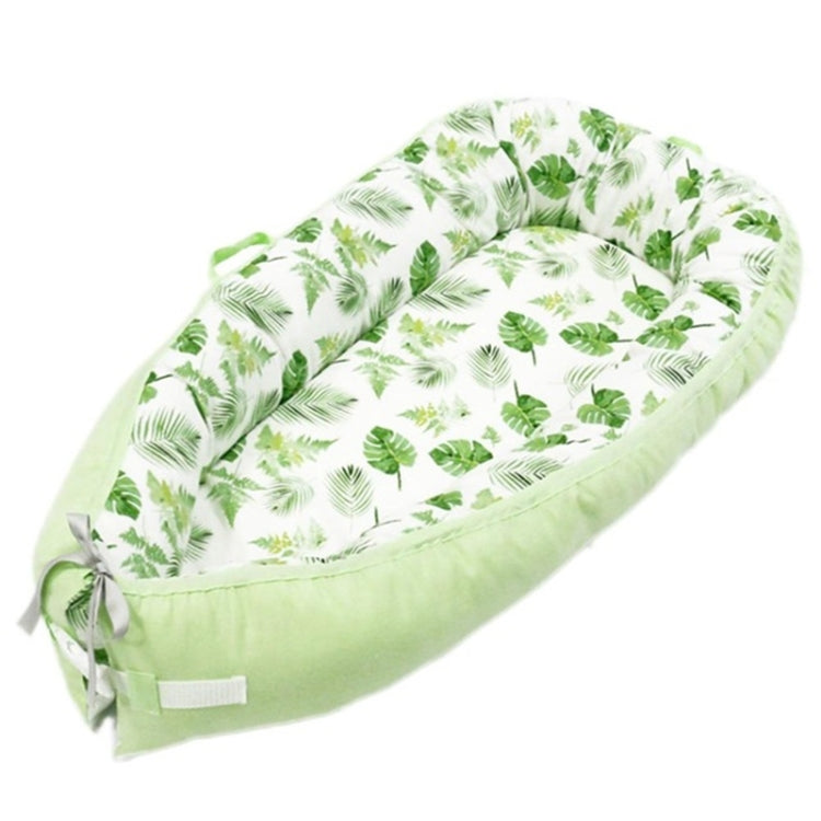 Baby nest bed with green leaf print inner and light green base, with side bow ties