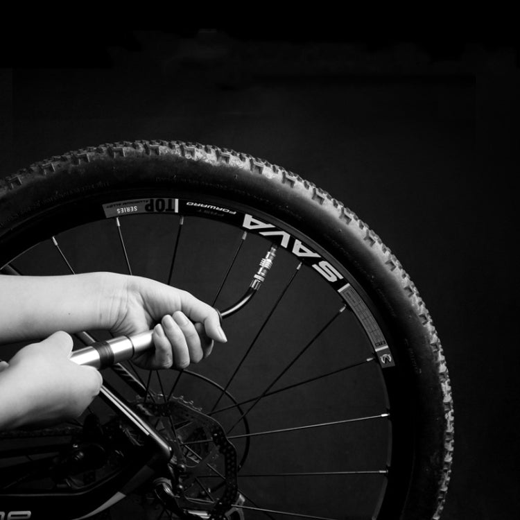 Mini bicycle pump inflating a bike tire, showing silver barrel and black nozzle