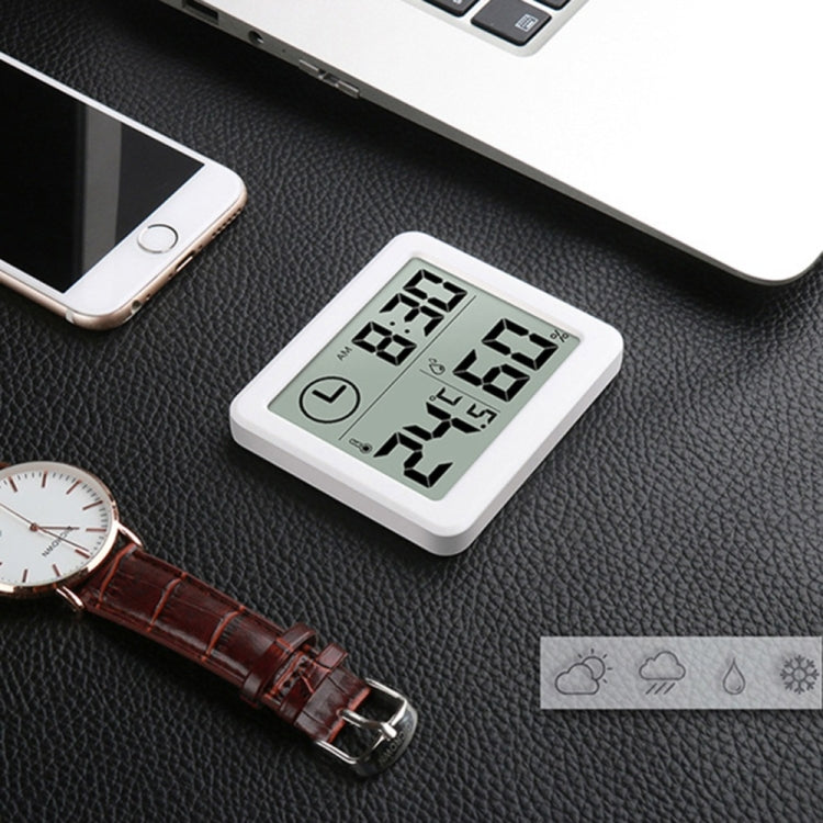 White LCD temperature and humidity monitor clock on dark surface with digits