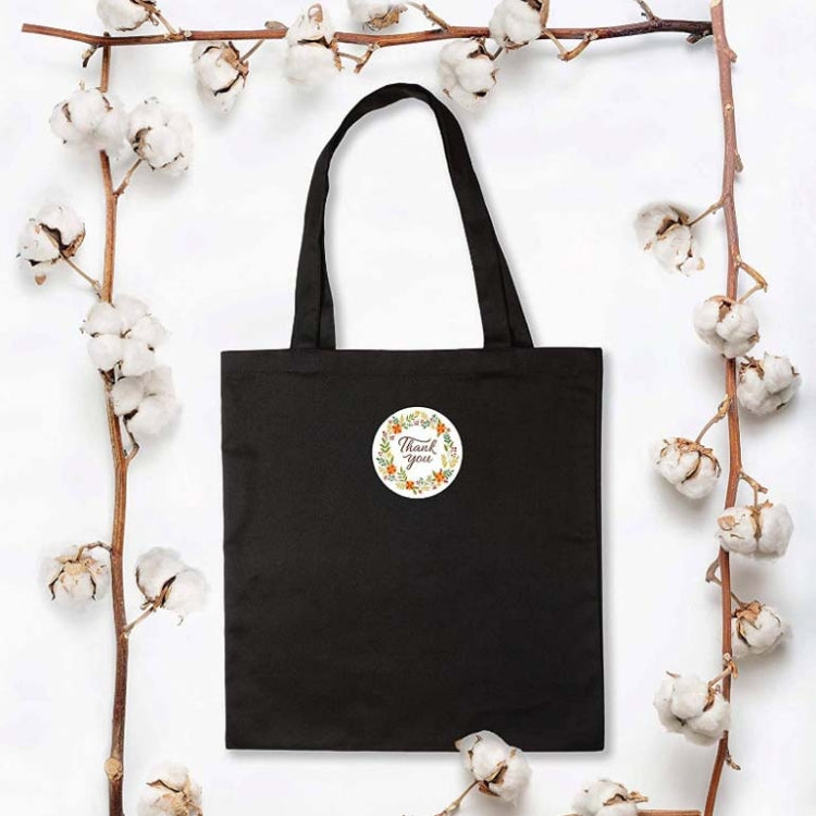 Black tote bag with small round thank you sticker in floral wreath style