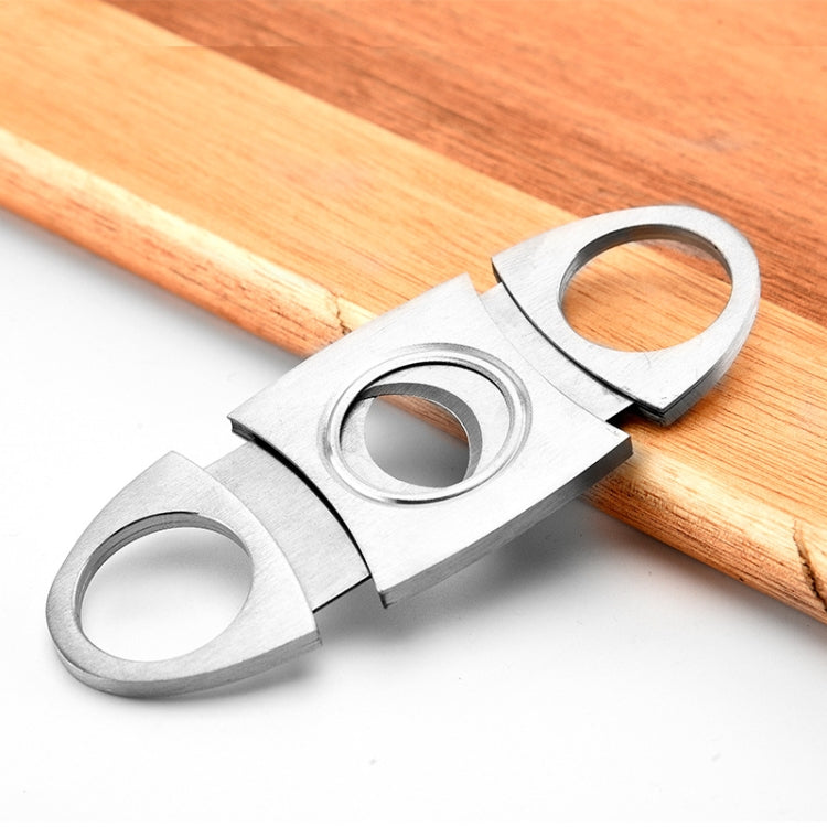 Stainless steel cigar scissors on wooden board with three circular rings and blade