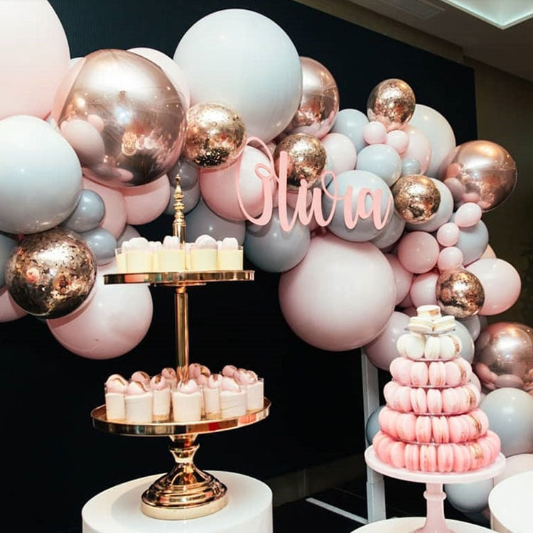 Macaron-style latex balloon set with blush and rose-gold balloons around a small cake stand