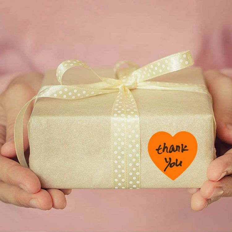 Orange heart “thank you” sticker on a gift box with pale ribbon