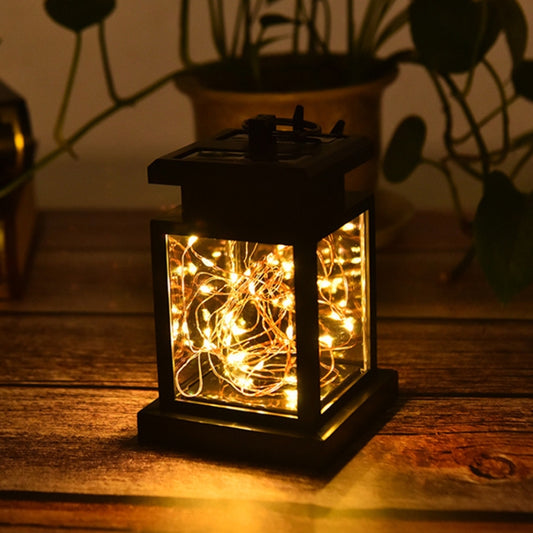 Solar black lantern outdoor light with glowing warm bulbs inside clear glass frame