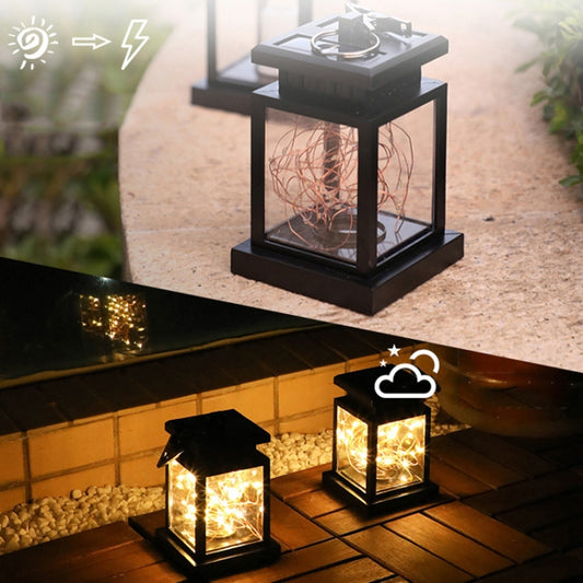 Solar lantern light with warm glow, black square frame, glass sides, copper-wire coils