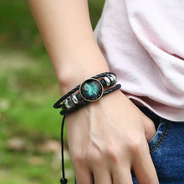 Black leather wrap bracelet with turquoise zodiac emblem shown on wrist