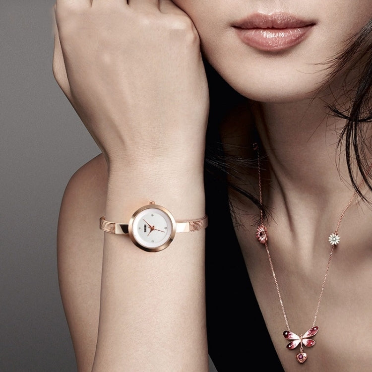 Rose gold ladies wristwatch with mesh band worn on wrist, round white dial