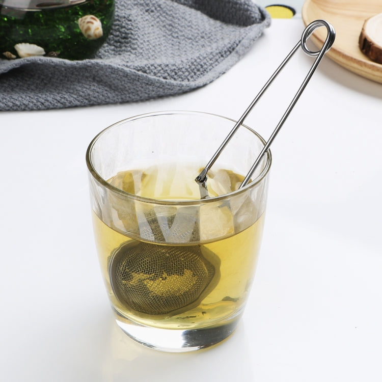 Stainless steel sphere mesh tea infuser resting in a glass cup