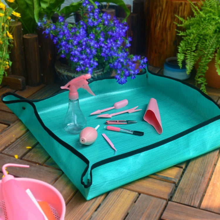 Green waterproof potting mat with black trim and grommet corners on a work surface