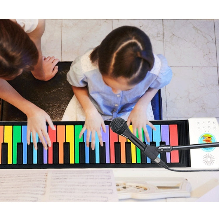 Children playing foldable roll-up piano with multicolor keys and handheld microphone