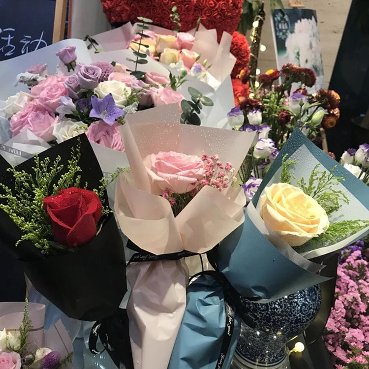 Flower bouquet assortment wrapped in translucent matte paper in pink, red, green, and blue