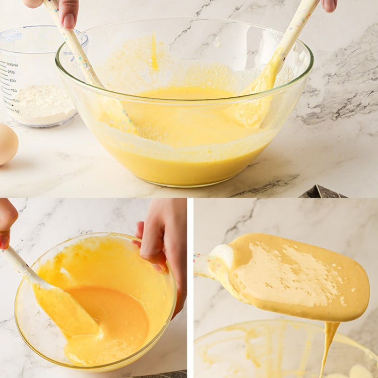 White speckled pastry brush stirring and spreading pancake batter in a glass bowl