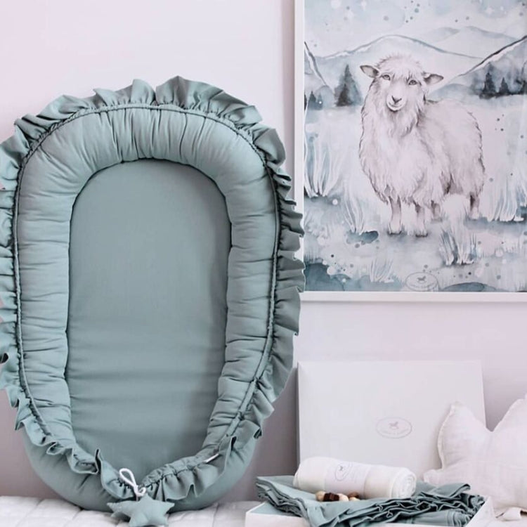 Blue-green portable newborn bed mat with wide ruffled rim and padded base