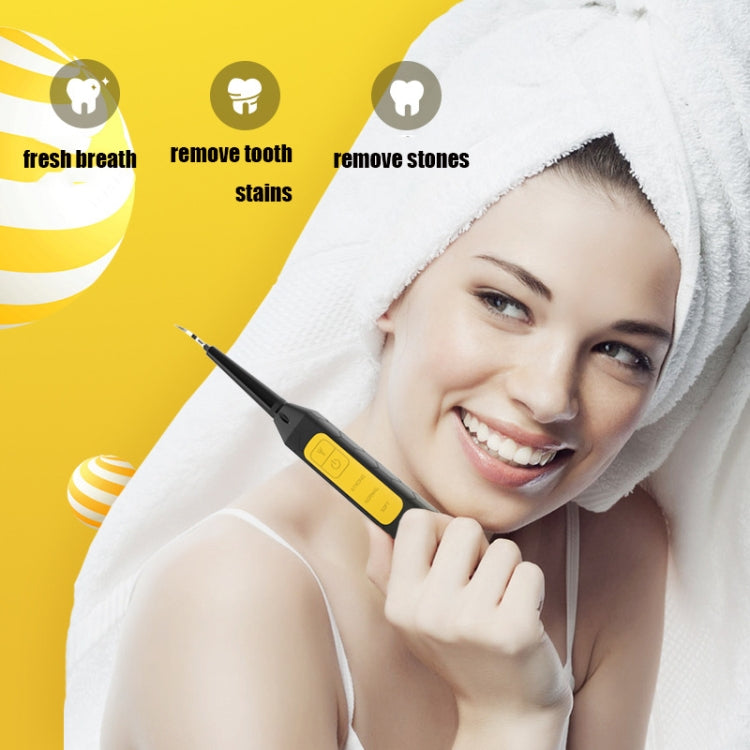 Black electric oral cleaning tool held near a smiling person in a towel