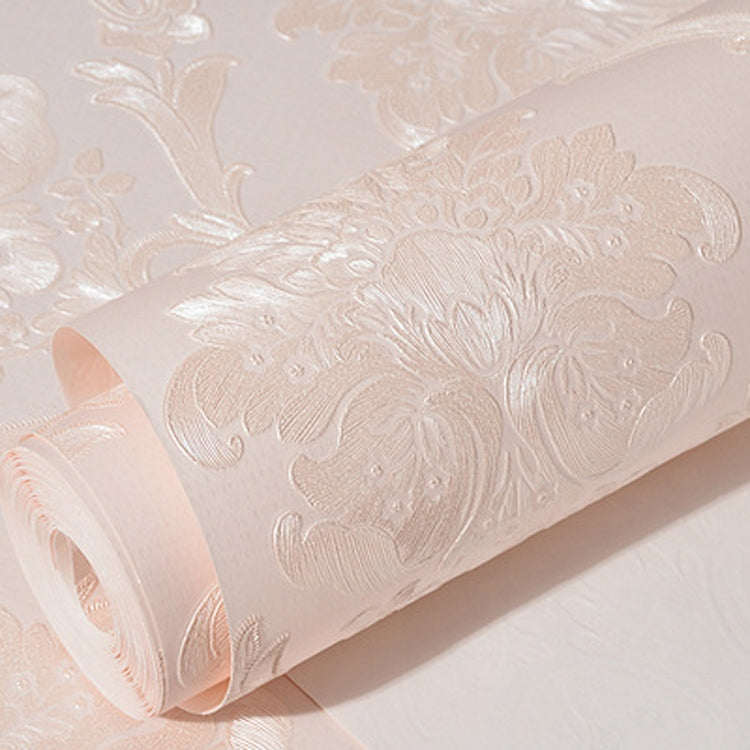 Pink damask embossed wallpaper roll with white raised floral and scroll pattern.