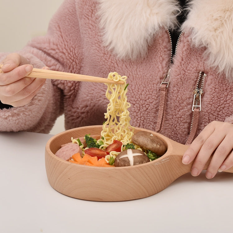 Light wooden bowl with handle holding noodles with vegetables and mushrooms inside