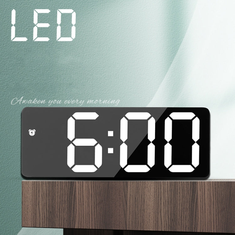 LED mirror bedside alarm clock close-up with dark face and white digital time.
