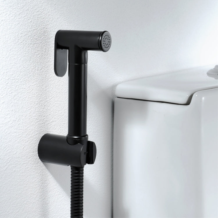 Black bidet shower sprayer mounted on wall with coiled hose to toilet