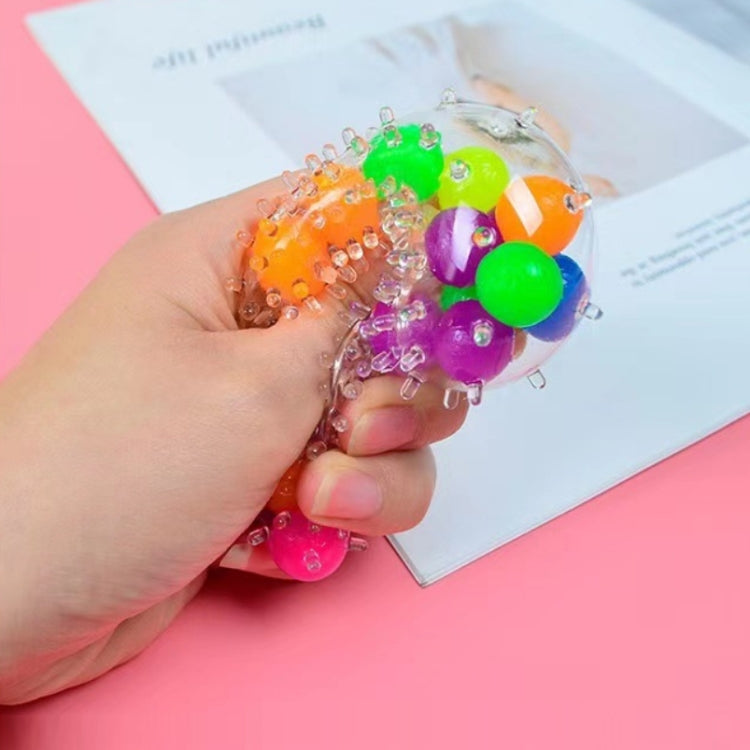 TPR vent ball decompression toy in hand, translucent spiky ball with green and purple beads