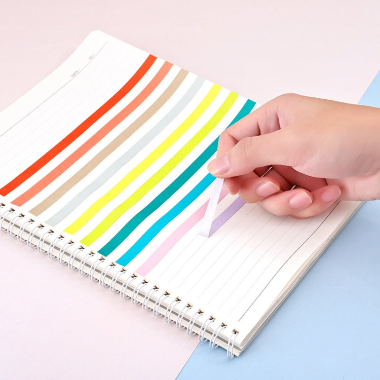Hand applying rainbow masking tape strips onto a lined notebook page