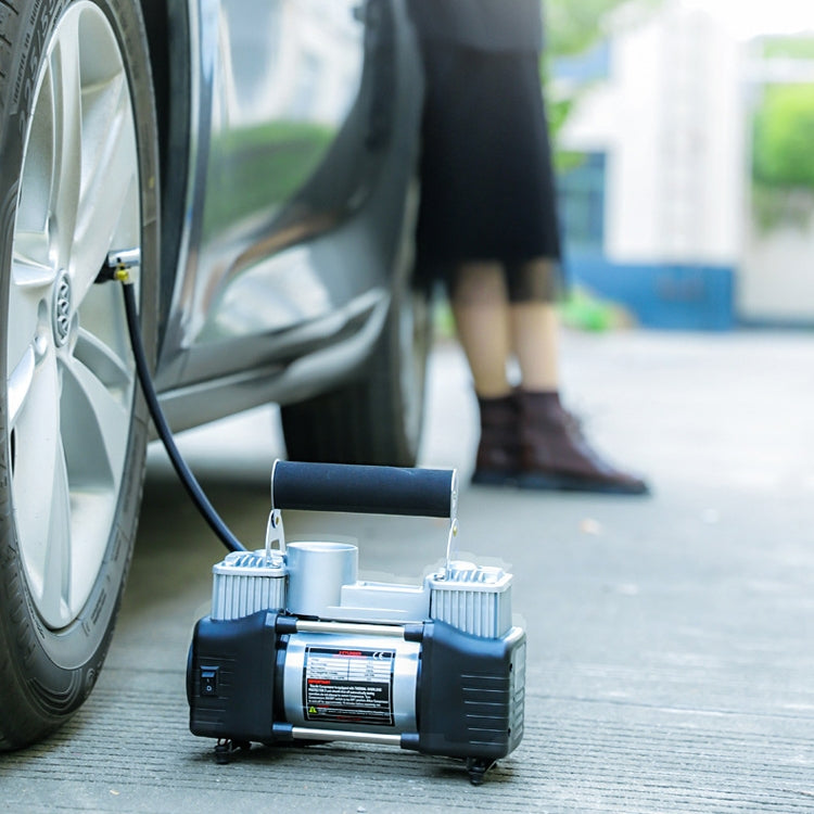 Portable air pump connected to a car tire with hose on the ground