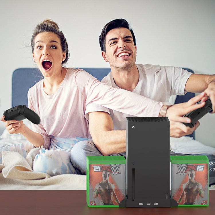 Xbox cooling base with disc storage shown in use beside controllers on a bed