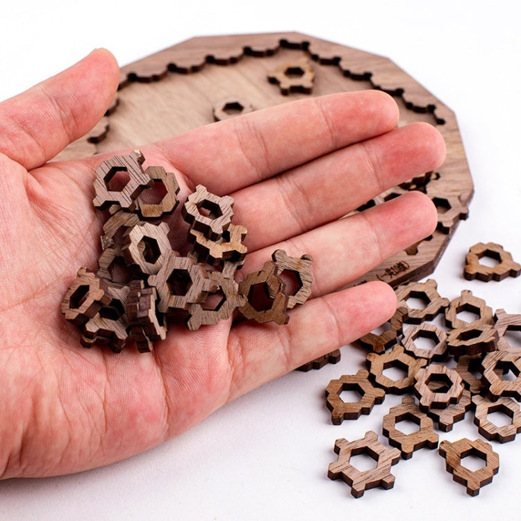 Hand holding small wooden interlocking puzzle pieces in front of wooden board